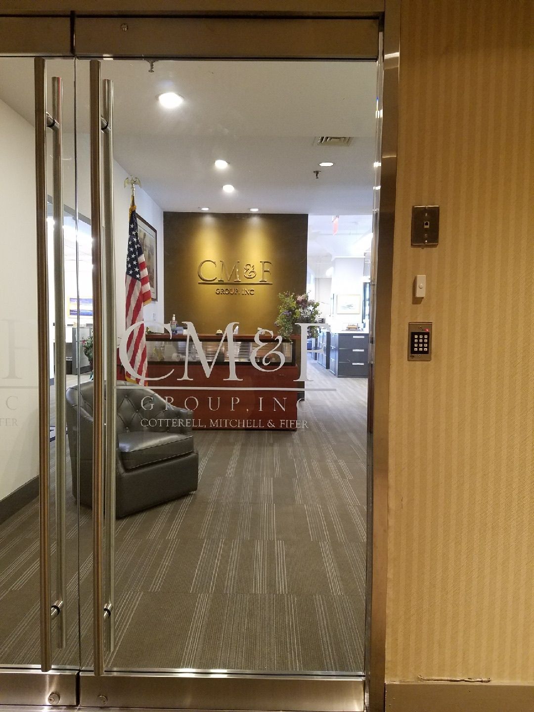 CM&F Group logo integrated into custom Herculite glass door — corporate branding on commercial glass entry system, Manhattan NYC