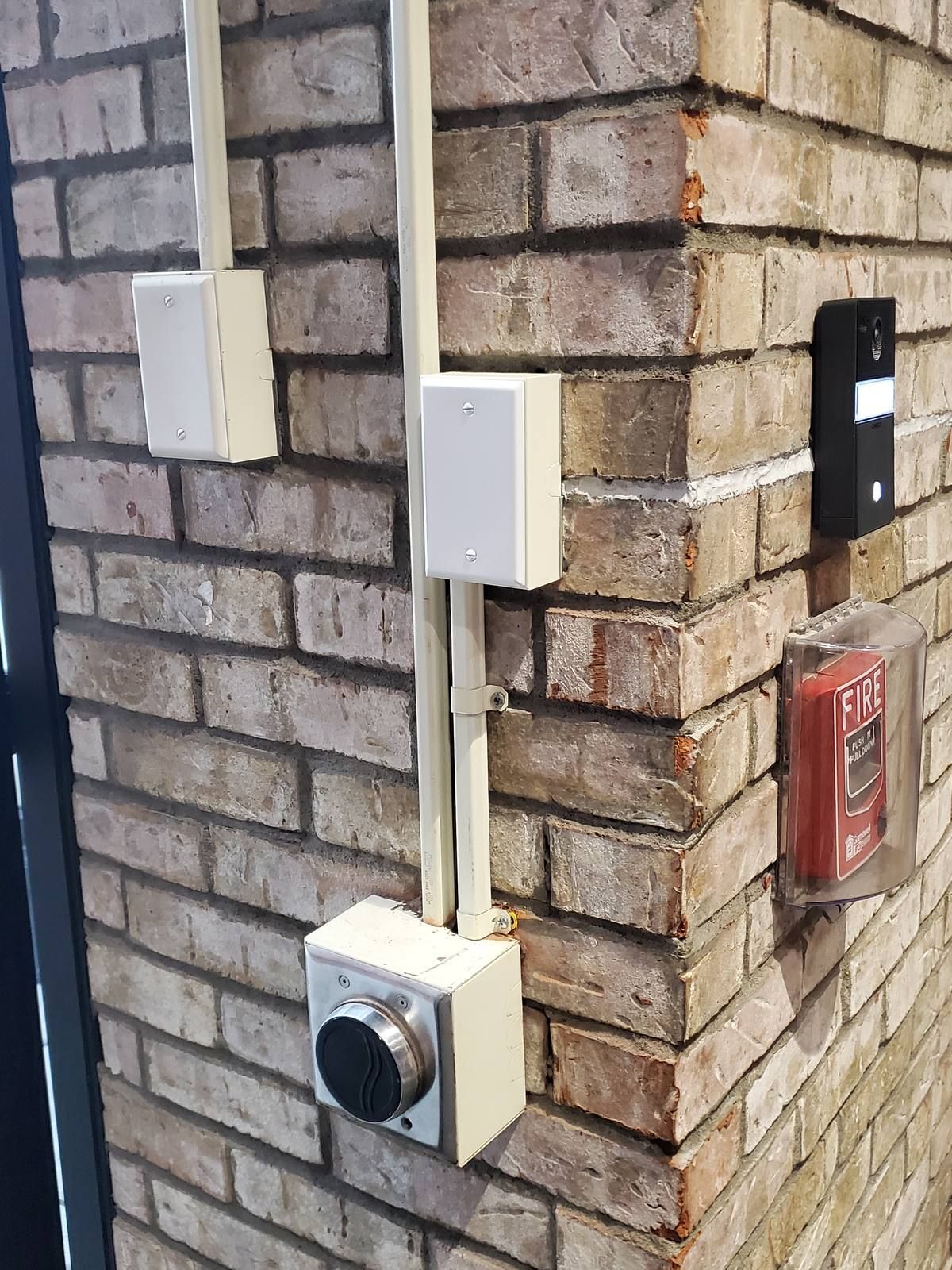 Intercom wiring run in white surface raceway on exposed brick at a NYC hotel entrance