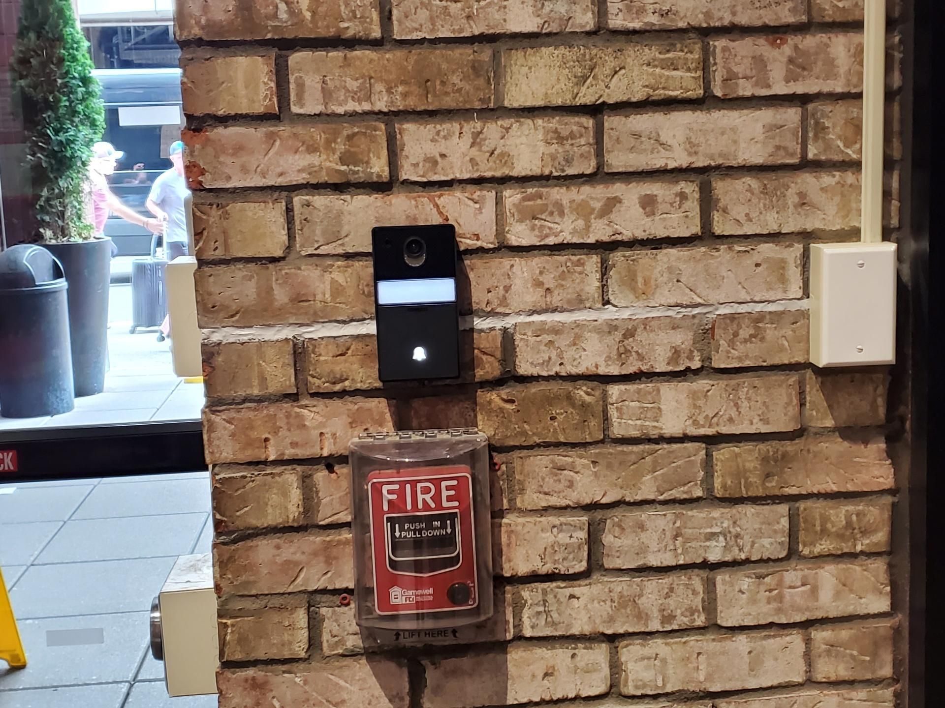 Comelit video intercom door station on an exposed brick column at a Times Square hotel entrance, Manhattan
