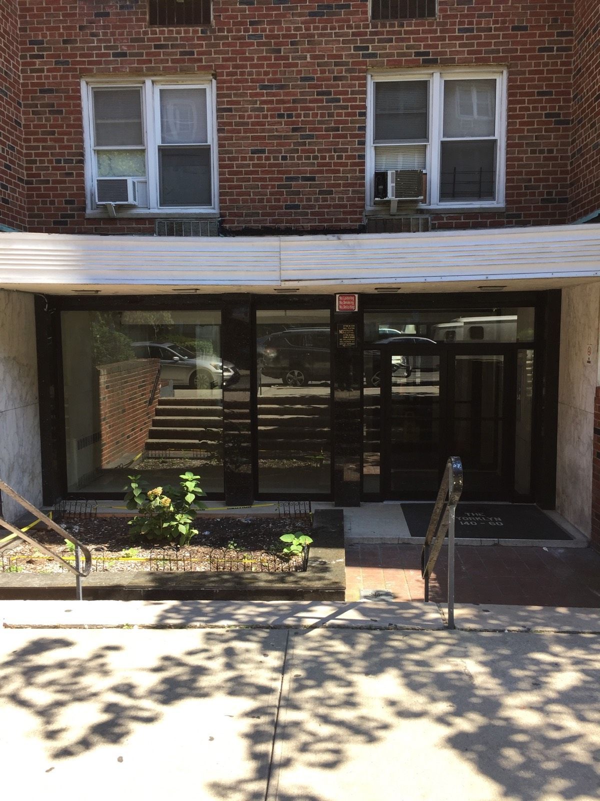 New black aluminum commercial vestibule and entrance doors at a Flushing, Queens apartment building — exterior view