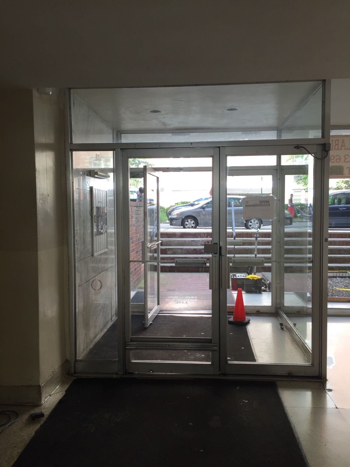 Worn original entrance doors before commercial vestibule replacement in Flushing, Queens