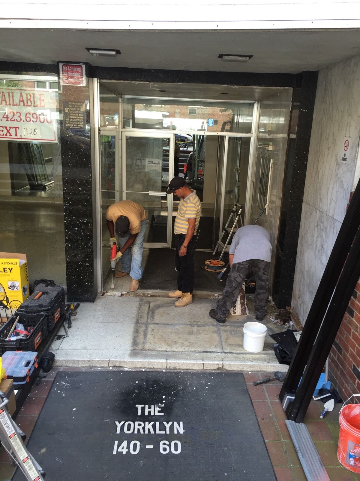 Removal of old vestibule doors during commercial entrance replacement in Flushing, Queens