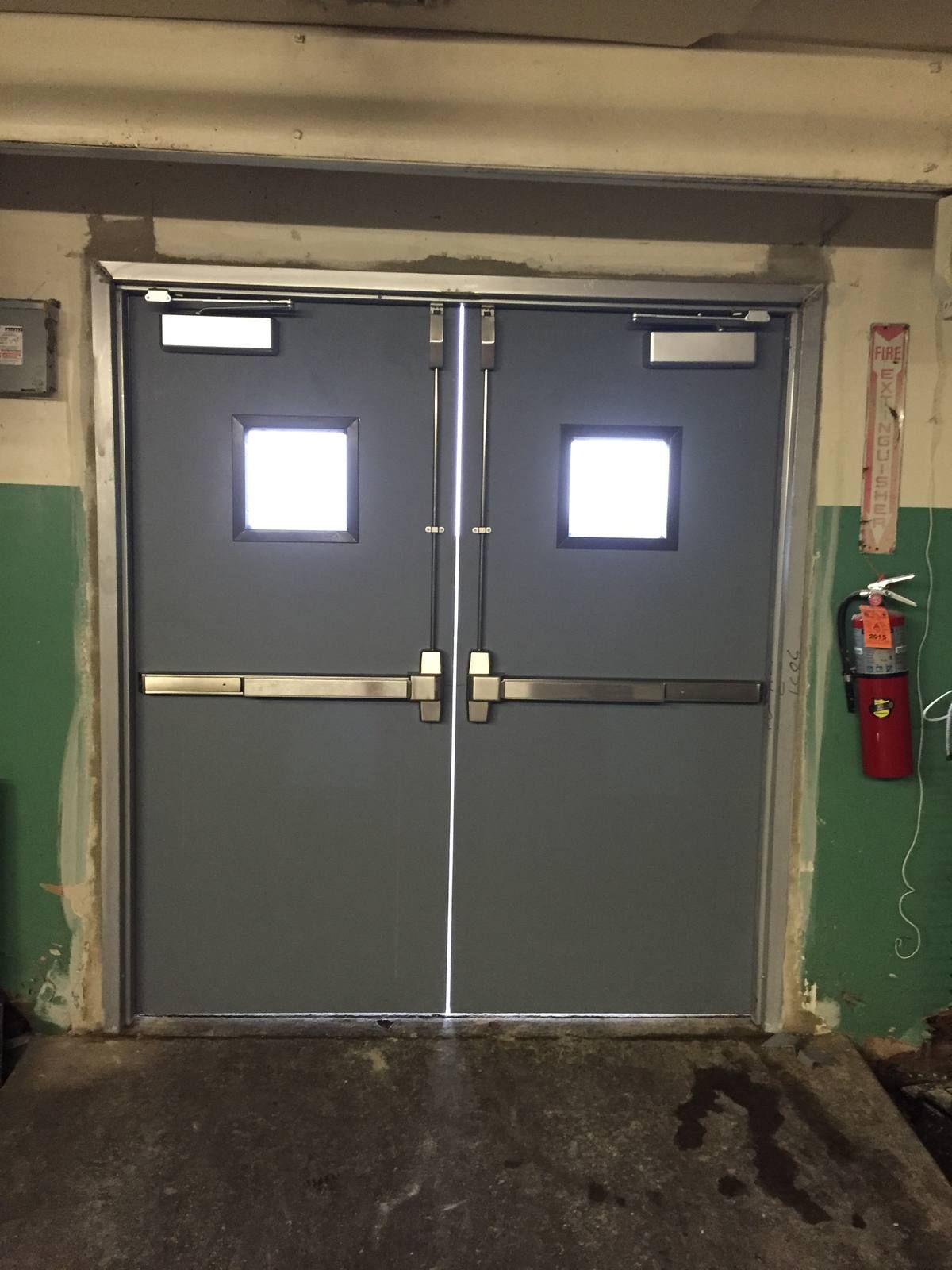 Hollow metal double doors with surface vertical rod panic bars, closers, and vision lites at a Bergen County supermarket