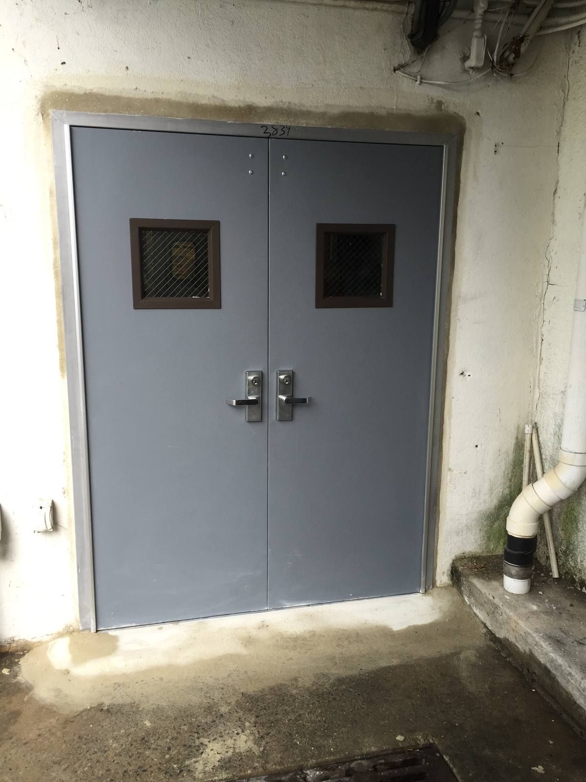 New gray hollow metal double doors with keyed lever trim and vision lites at a Glen Rock, NJ supermarket