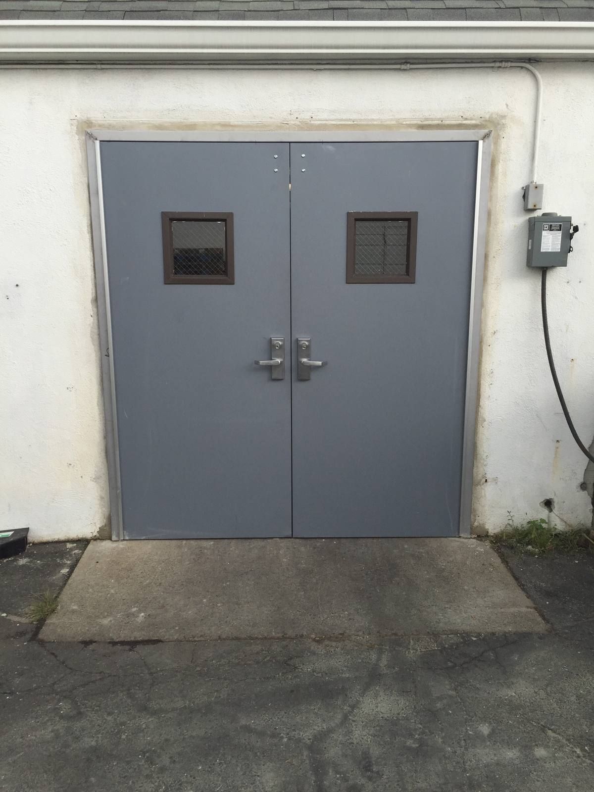 New hollow metal double doors at a supermarket service entrance with a concrete pad in Glen Rock, NJ