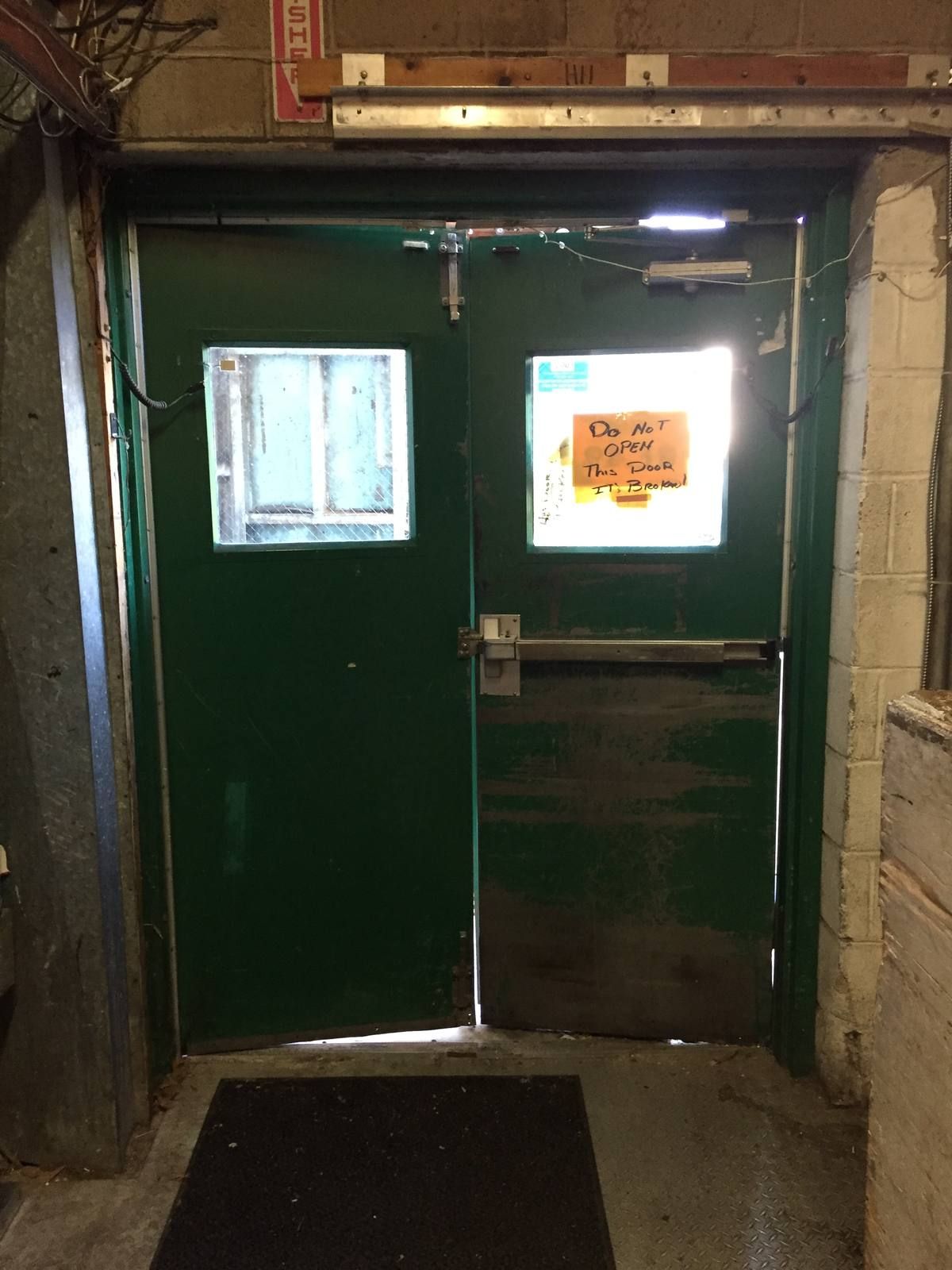 Inside view of worn green double doors with an old panic bar and a do-not-open sign in a Glen Rock, NJ supermarket