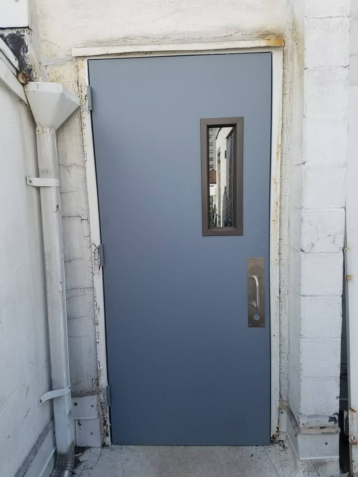 New hollow metal roof door with wire-glass vision lite and pull plate on a Manhattan apartment building rooftop