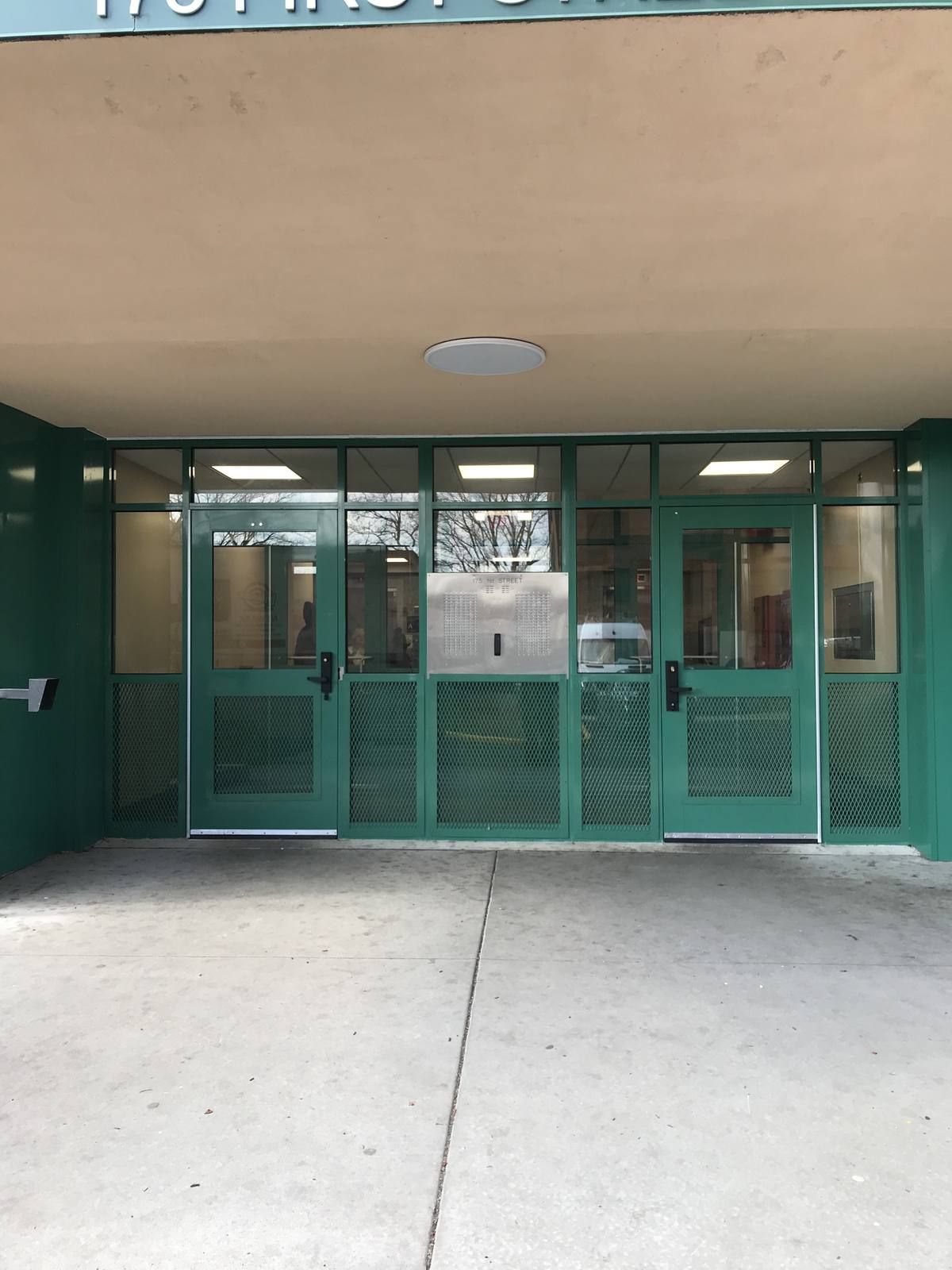 Double aluminum storefront entrance doors with mesh infill panels at 175 First Street, Newark NJ