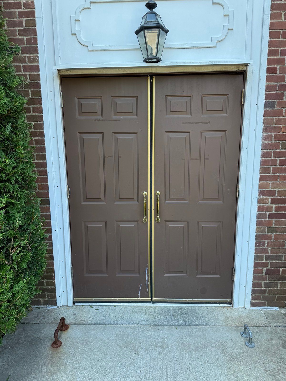 Exterior view of a side entrance door with brass push and pull hardware at St. Clare's Church, Staten Island