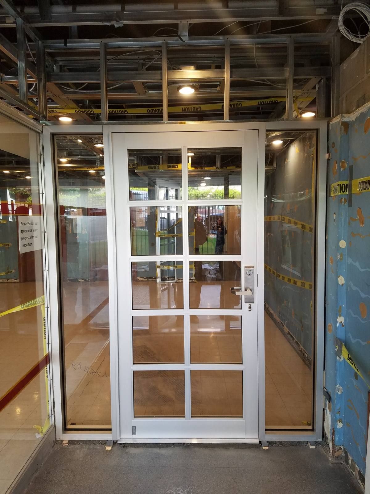 New grid-pattern aluminum vestibule door with lever lockset and sidelites inside a Yonkers apartment lobby