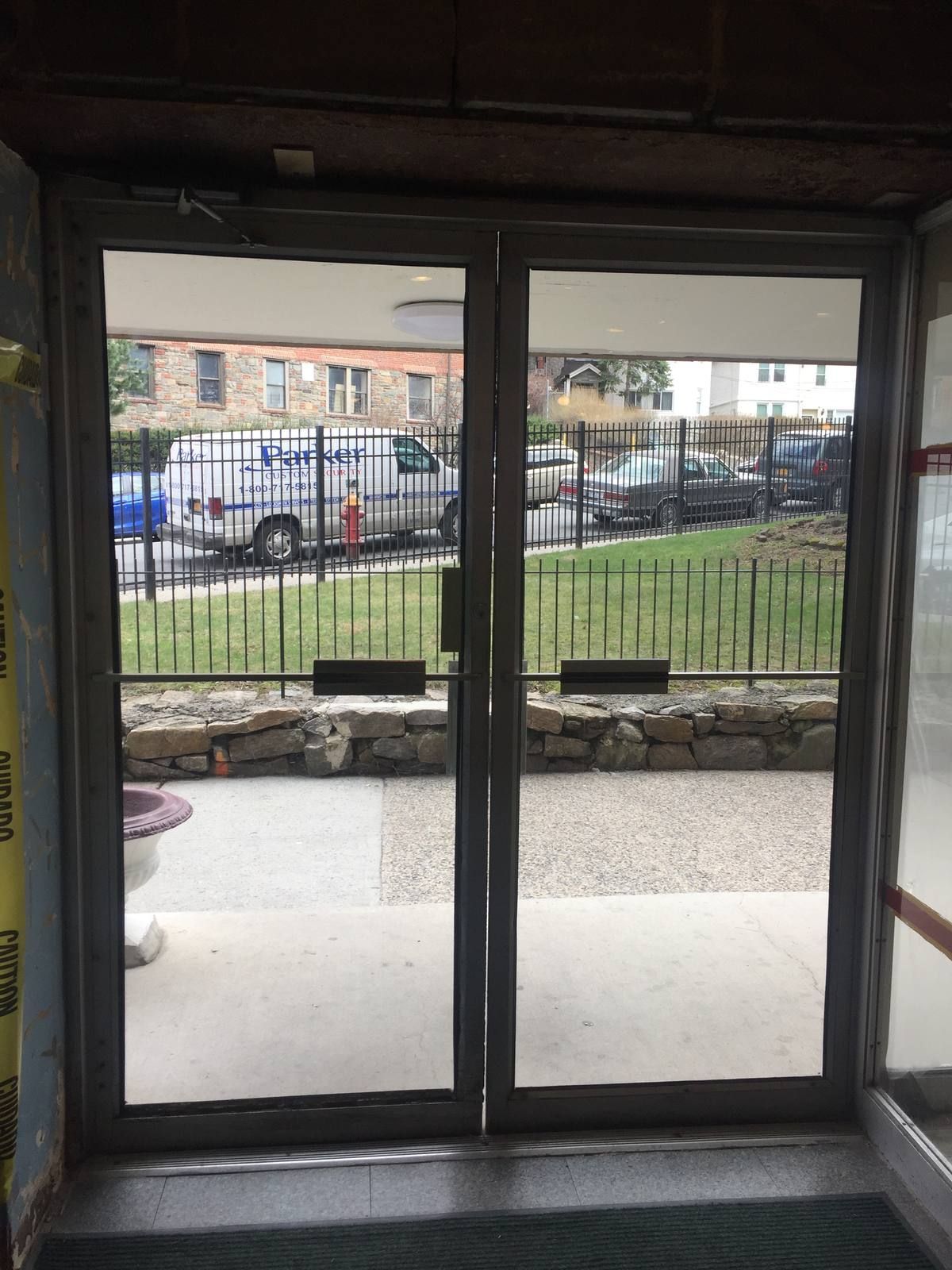 Old dark-framed glass double entrance doors at a Yonkers apartment building before replacement