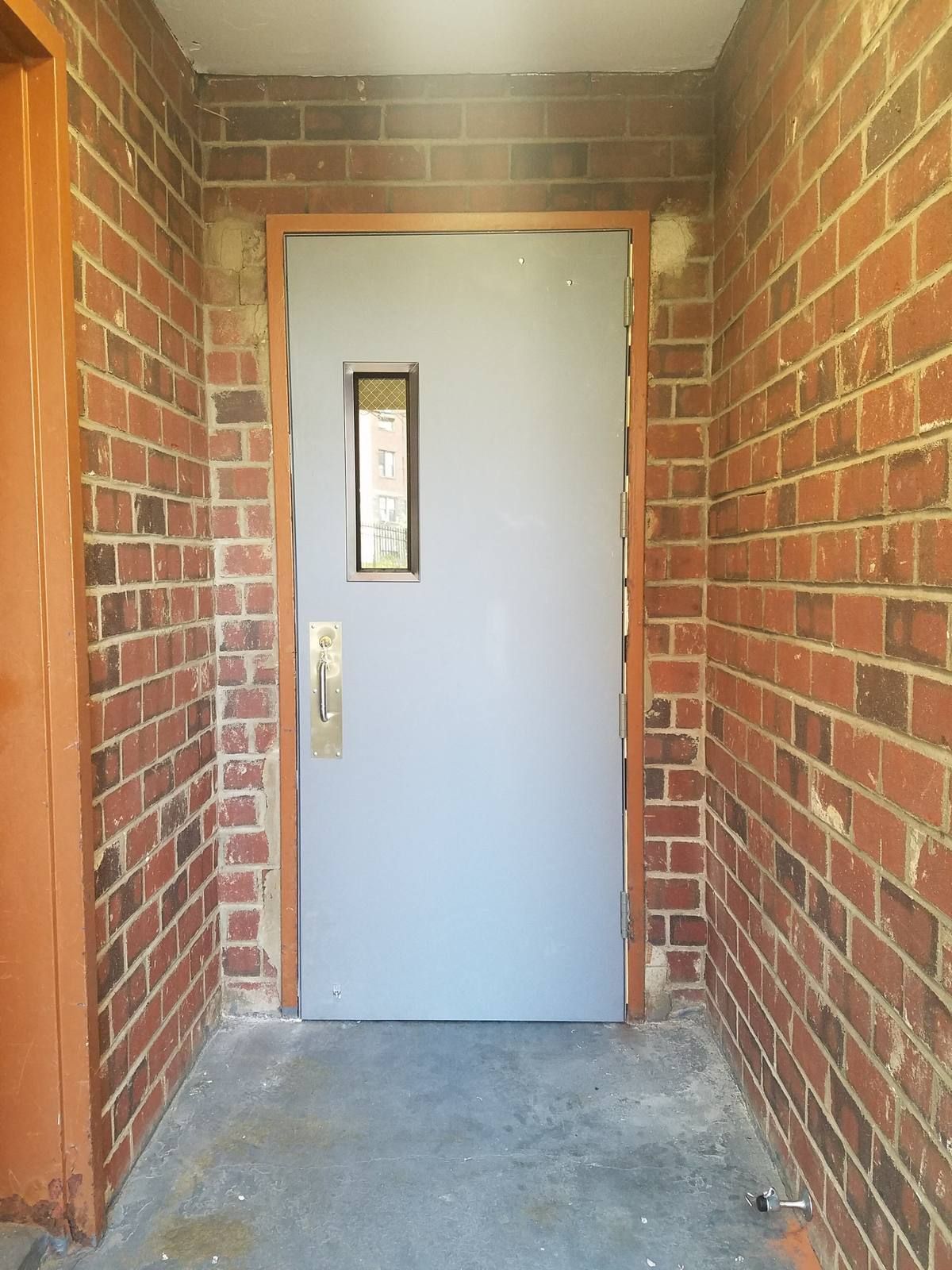 New hollow metal door with narrow vision lite and pull trim in a brick hallway in Yonkers, NY