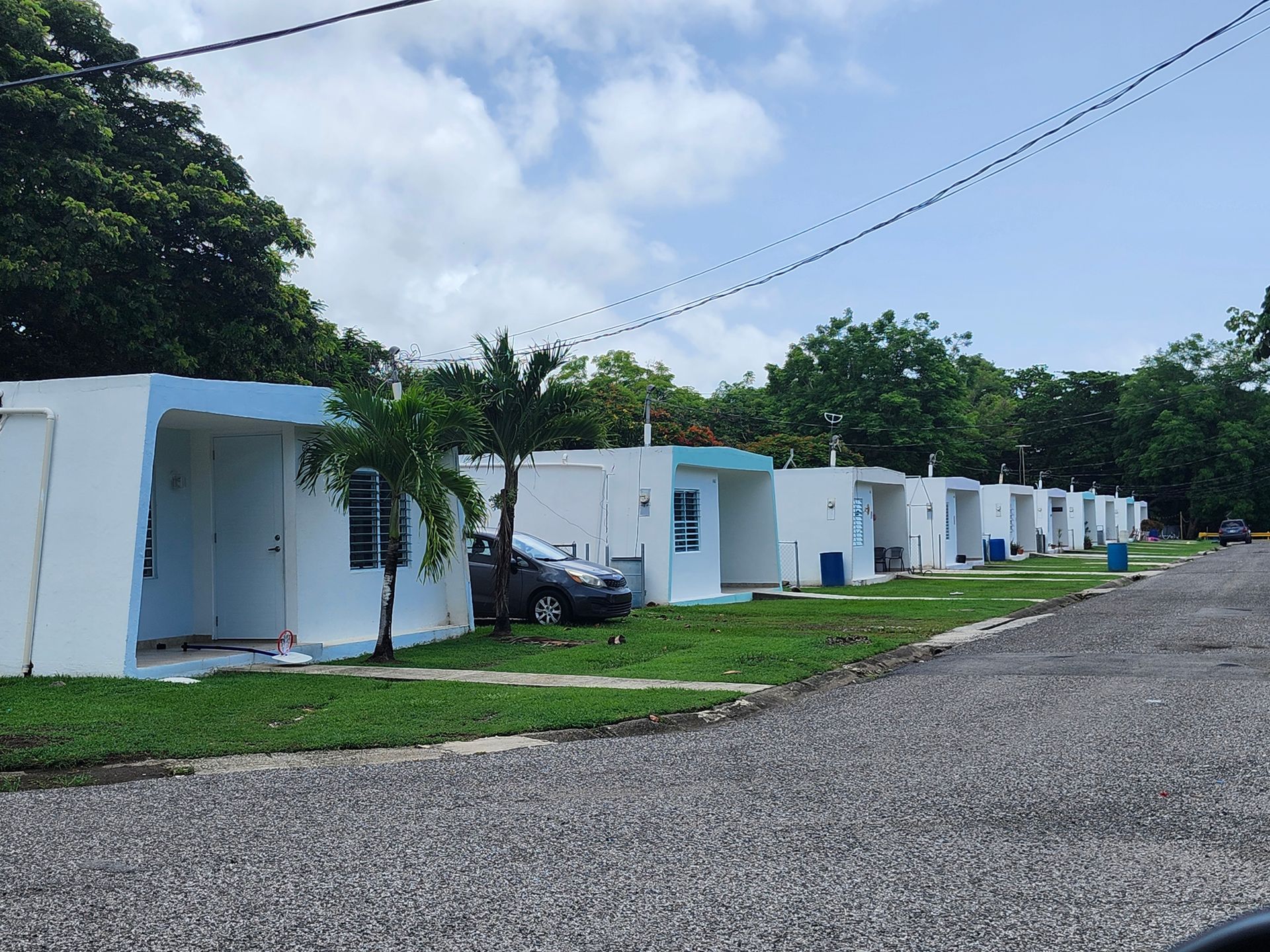 Row of small white cabins along a gravel road under a partly cloudy sky