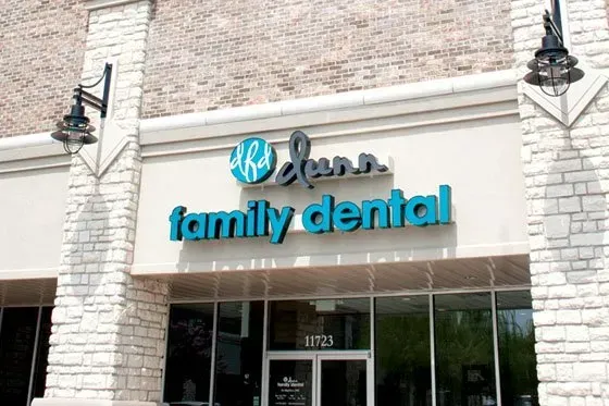Sign for Penn Family Dental, blue and teal text on a white background, in front of a brick building.