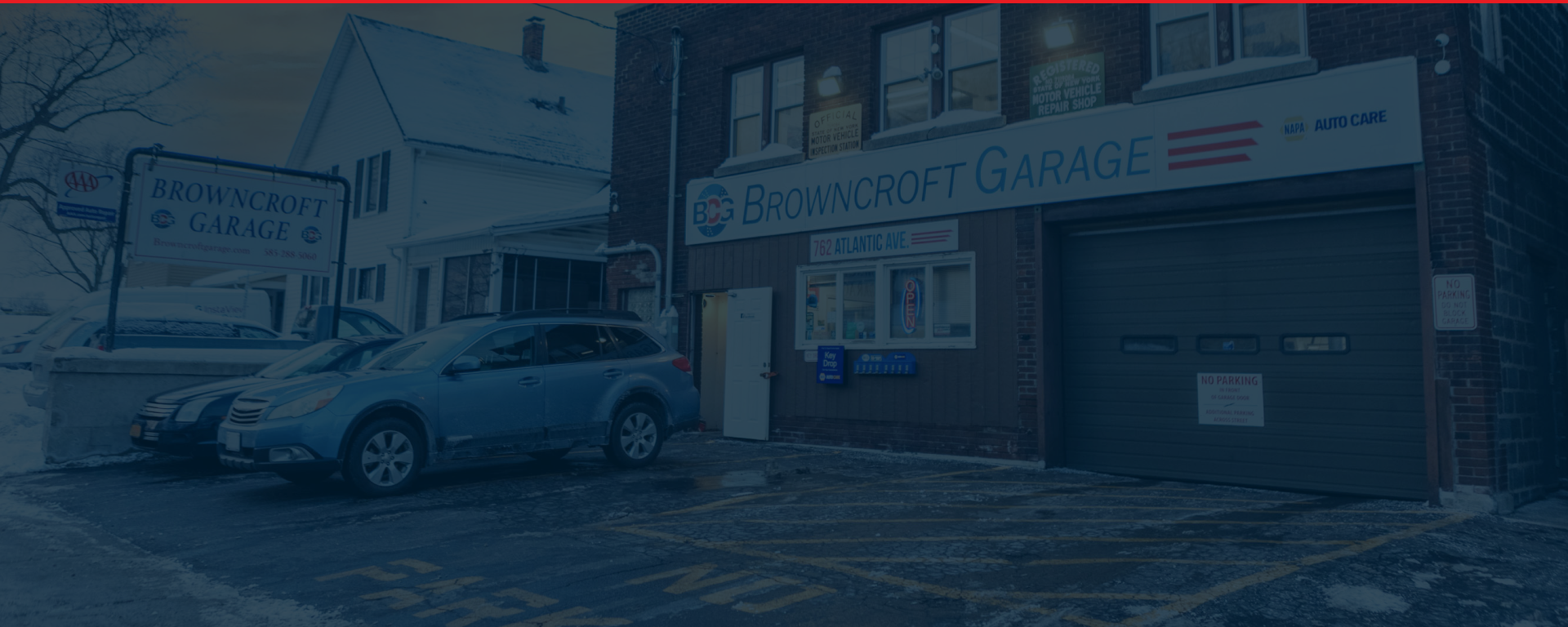 Blue SUV parked in front of a building with a garage sign on a wet street | Browncroft Garage