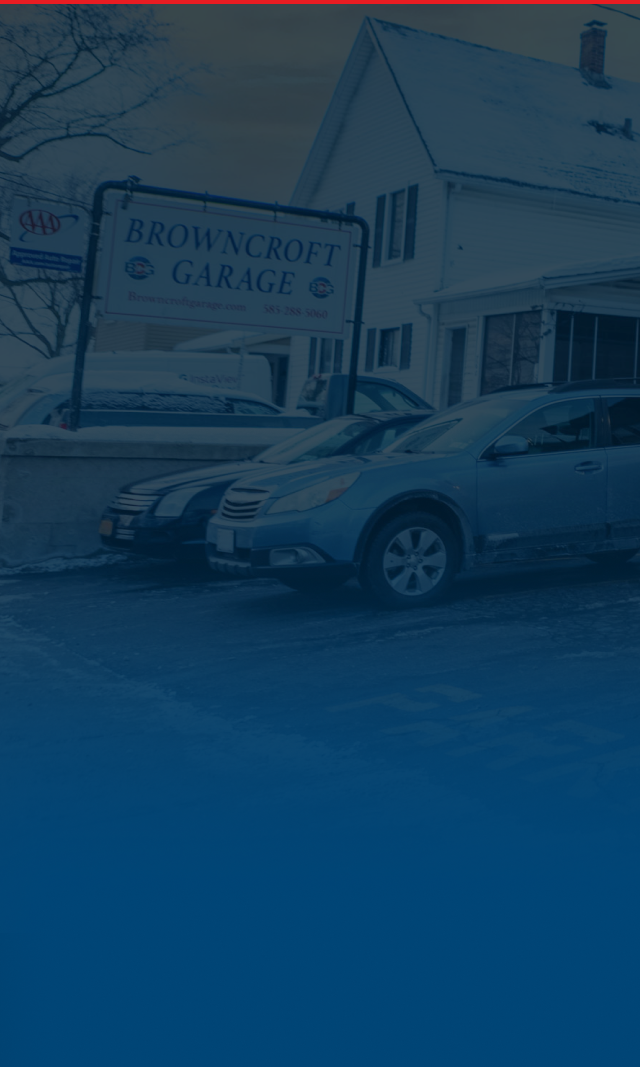 Blue SUV parked in front of a building with a garage sign on a wet street | Browncroft Garage