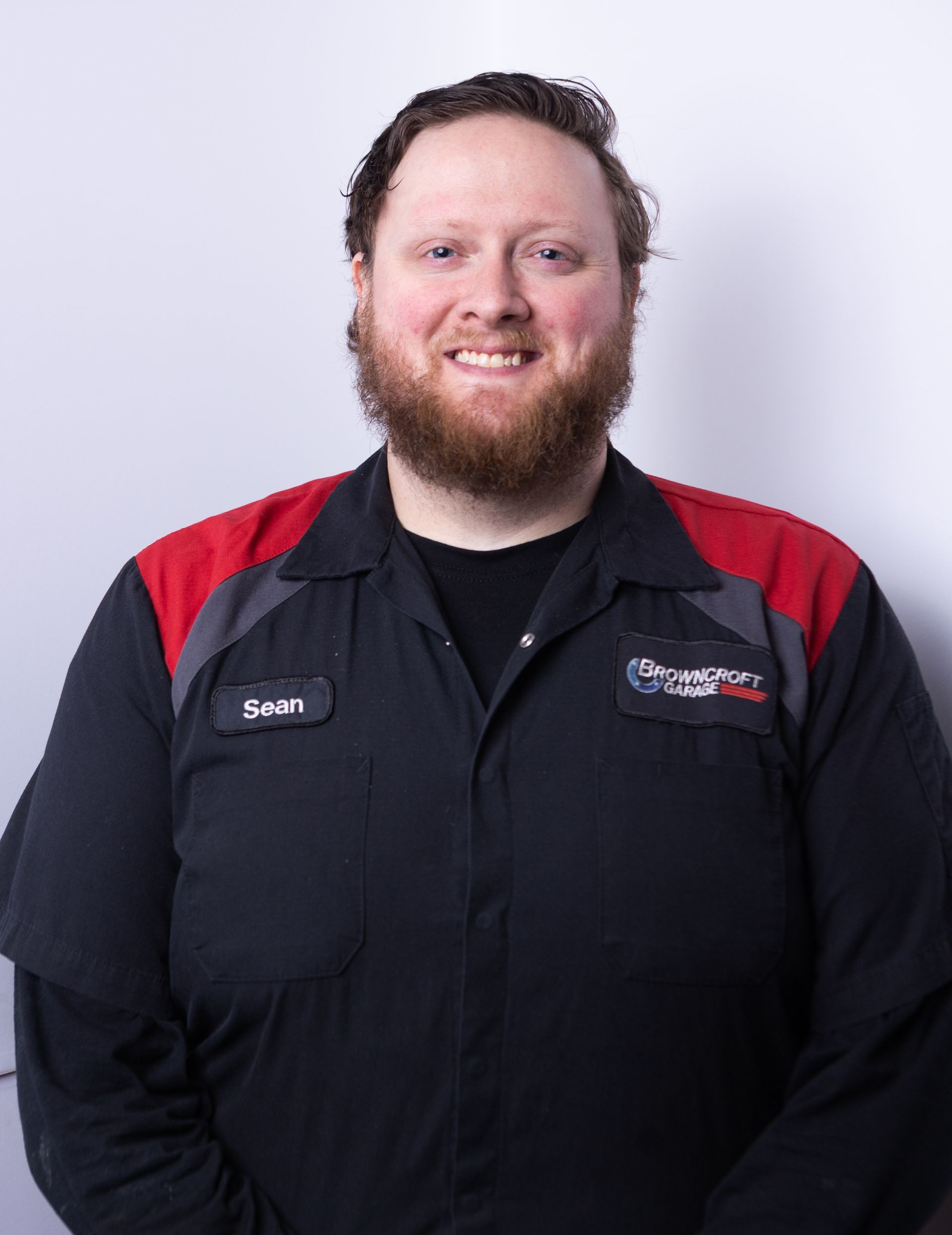 Smiling man in a black and red work shirt against a light background | Browncroft Garage