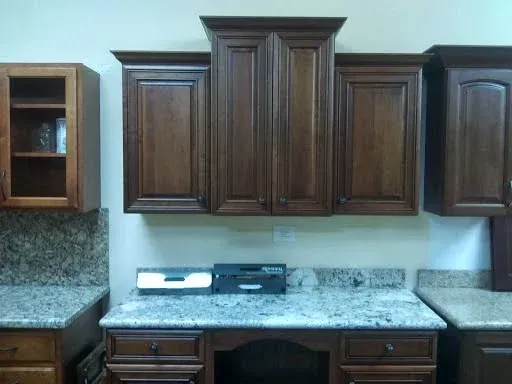 Kitchen cabinetry display with dark wood wall cabinets and a speckled granite countertop over a desk area.