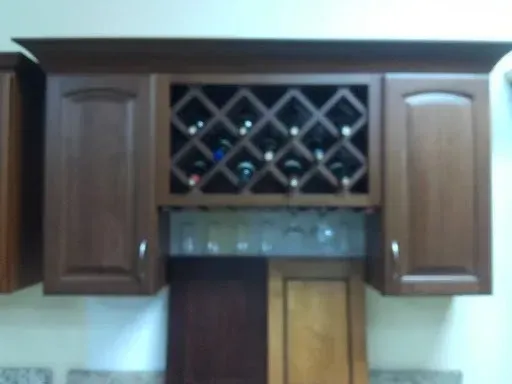 A dark wood cabinet featuring a central wine rack with bottles, wine glass storage underneath, and flanking cabinet doors.