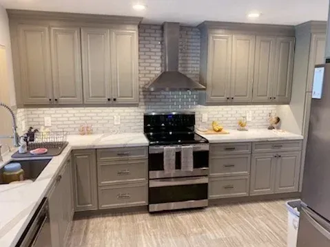 Modern kitchen with grey cabinets, a stainless steel range, and a white subway tile backsplash.
