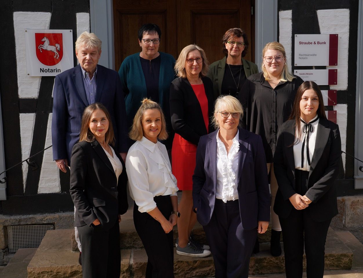 Eine Gruppe von Menschen posiert vor einem Gebäude für ein Foto.