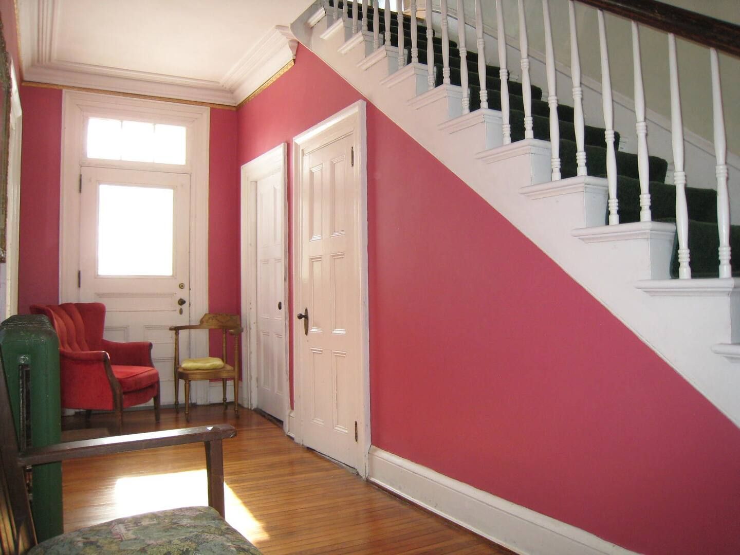 A hallway with pink walls and white stairs