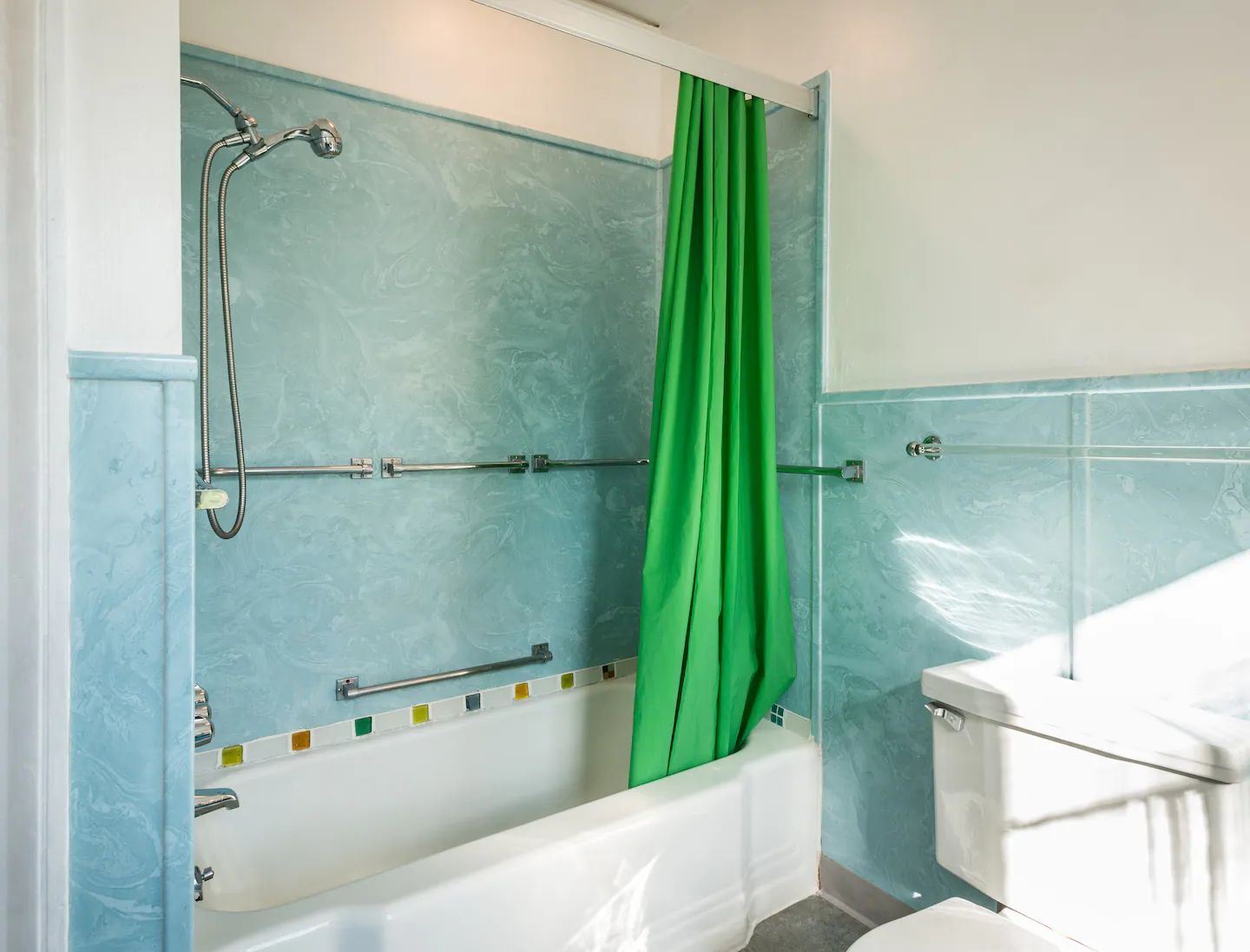 A bathroom with a green shower curtain and a bathtub