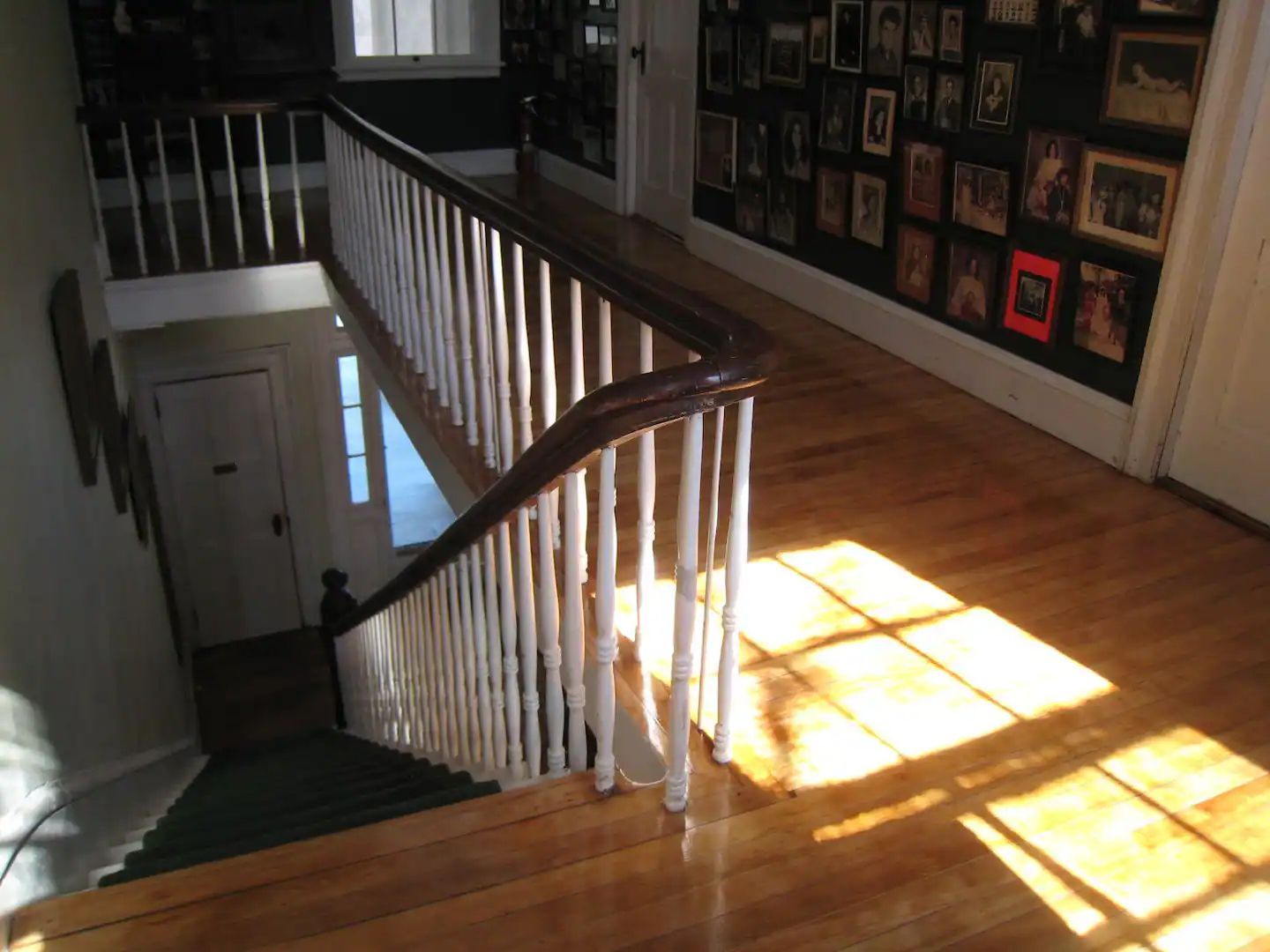 A staircase with a white railing and a wall full of pictures