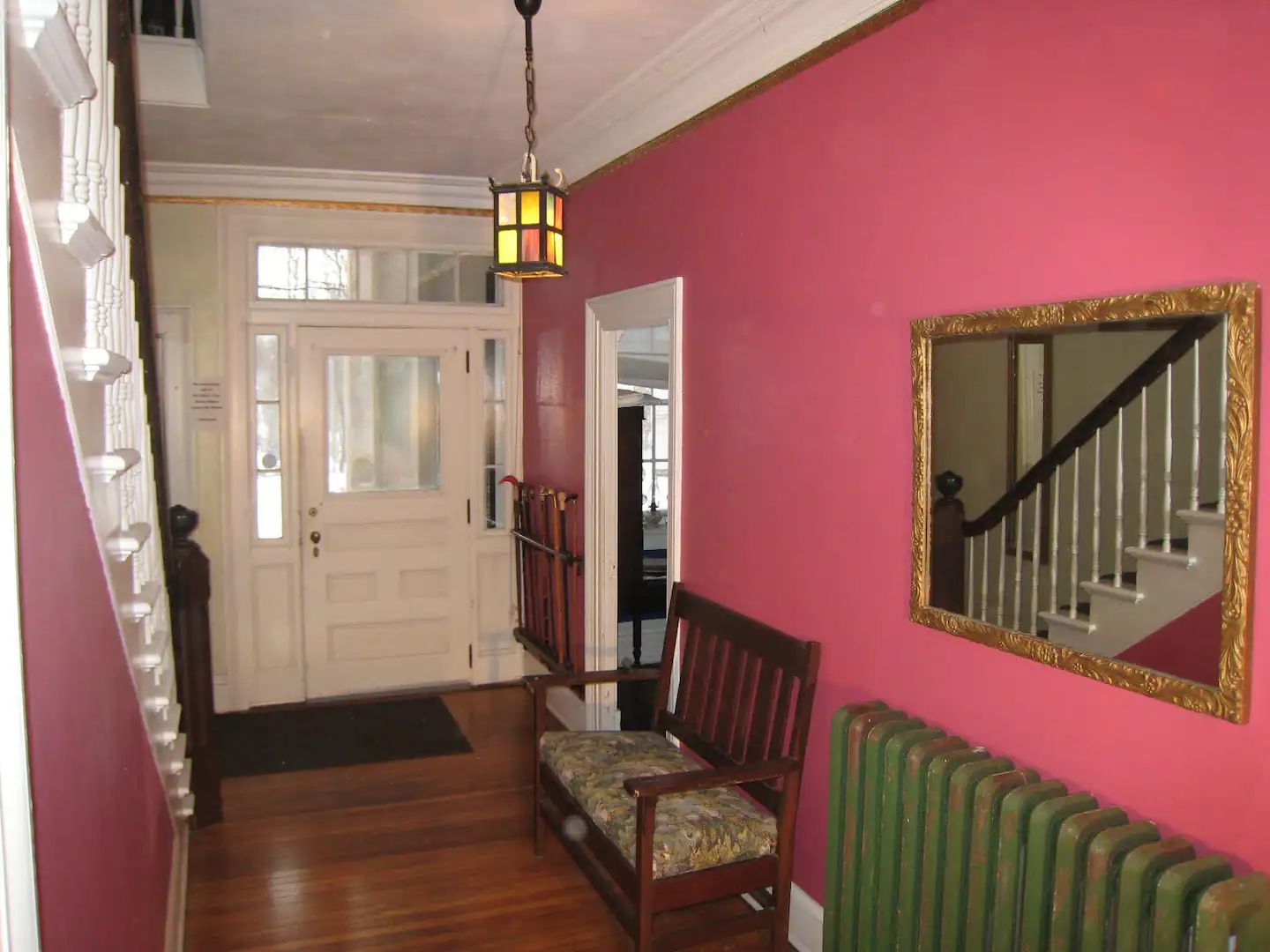 A hallway with pink walls and a green radiator