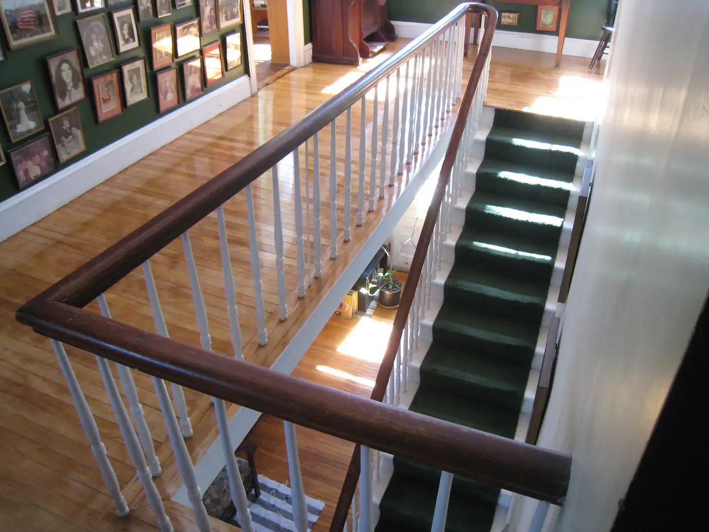 A staircase with a green carpet and a white railing