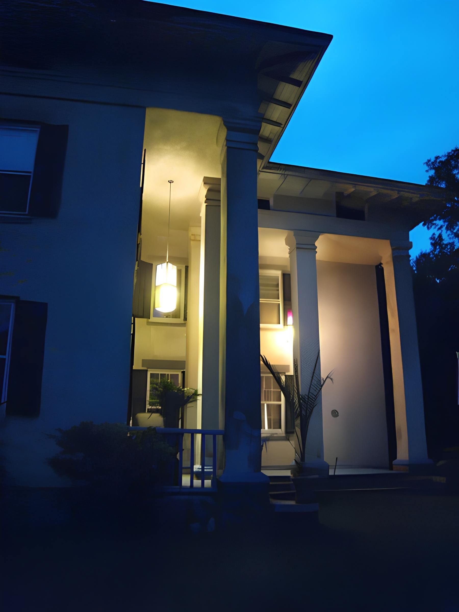 A house with a porch is lit up at night