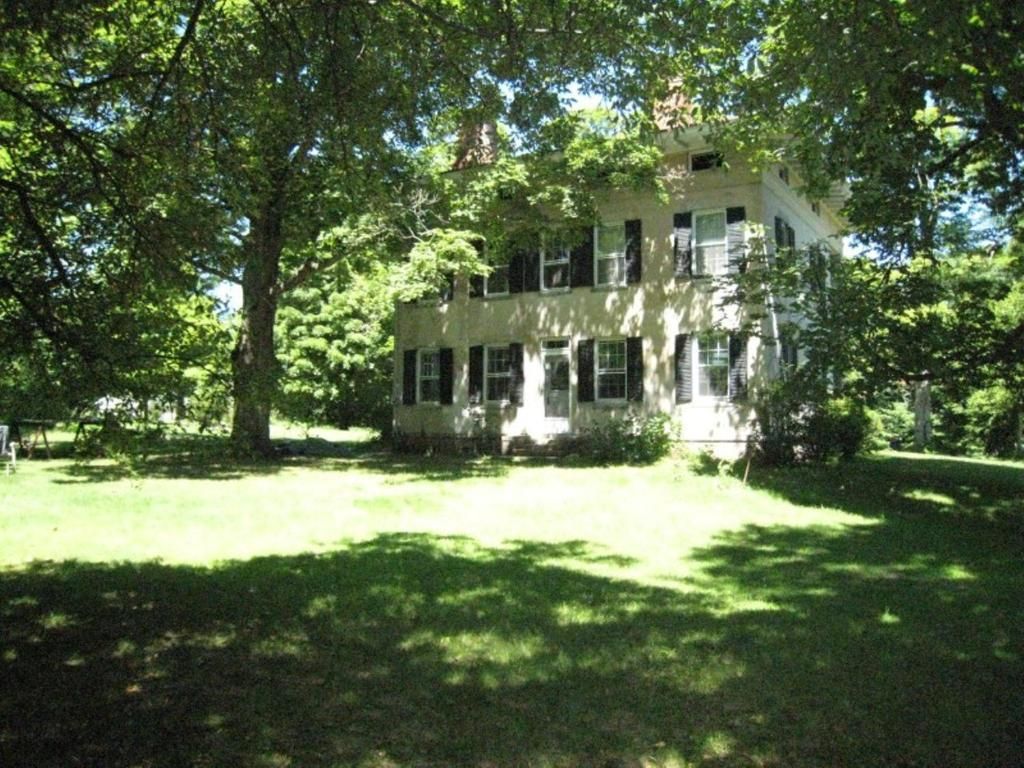 A large house is surrounded by trees on a sunny day