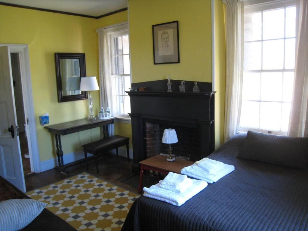 A bedroom with yellow walls and a fireplace
