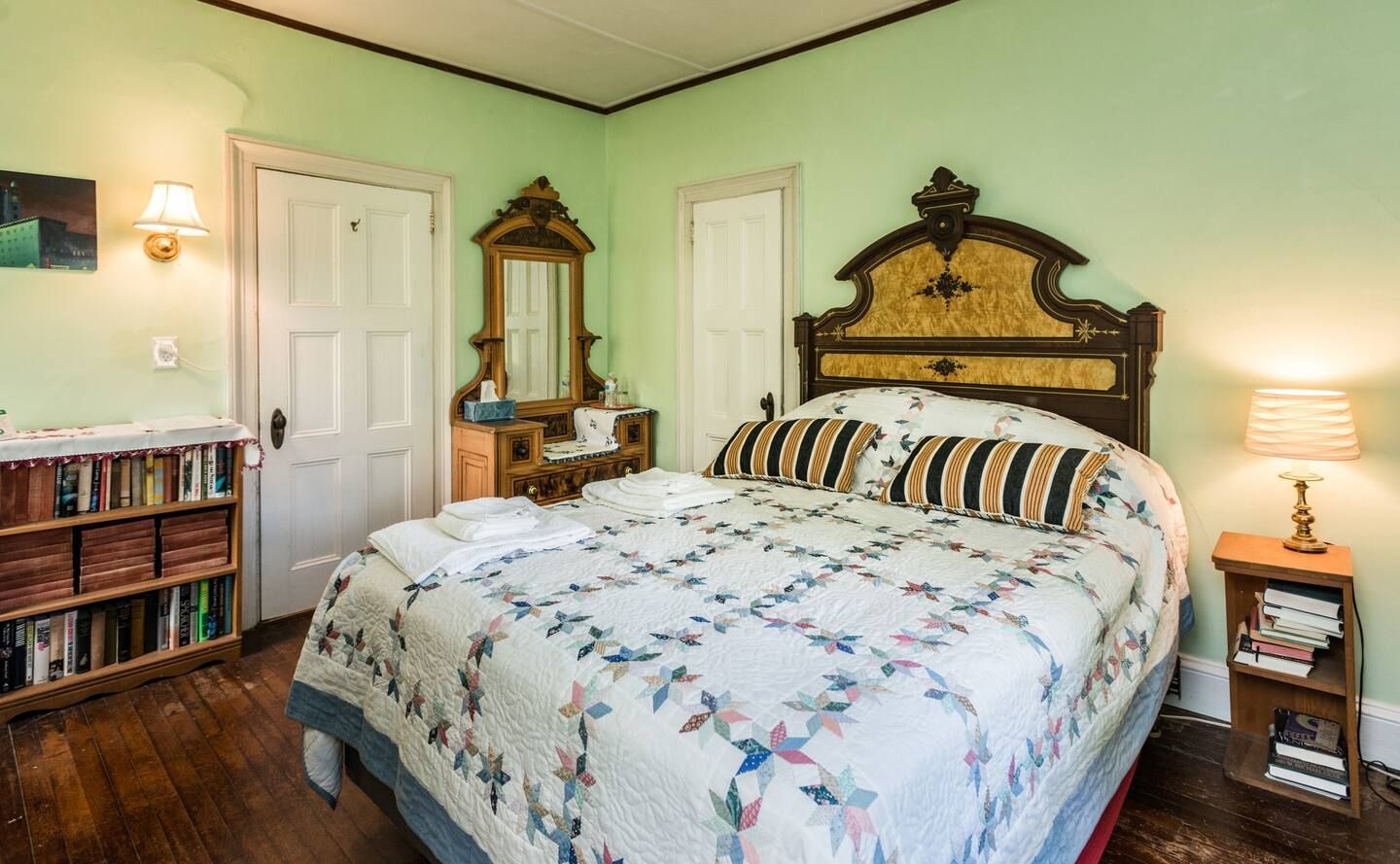 A bedroom with a bed , dresser , mirror and bookshelf.