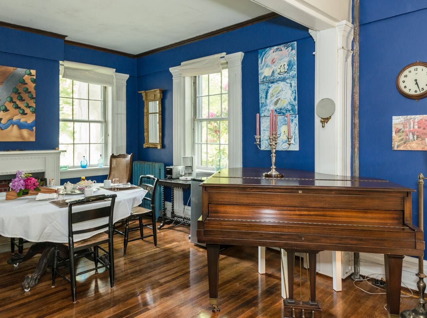 A living room with blue walls , a piano , a table and chairs.