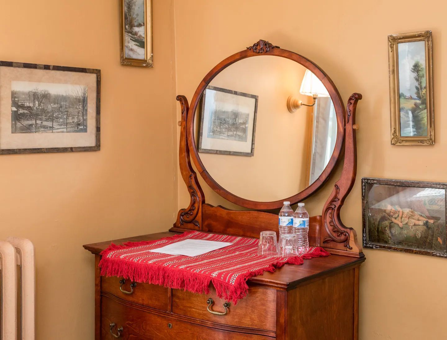 A dresser with a round mirror on top of it in a room.