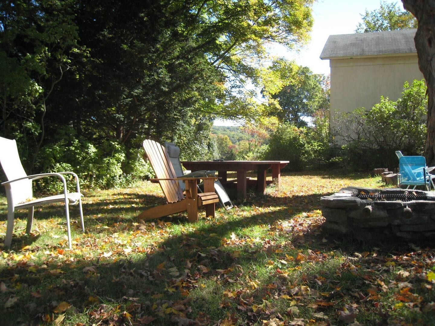 A fire pit with chairs and a table in the backyard