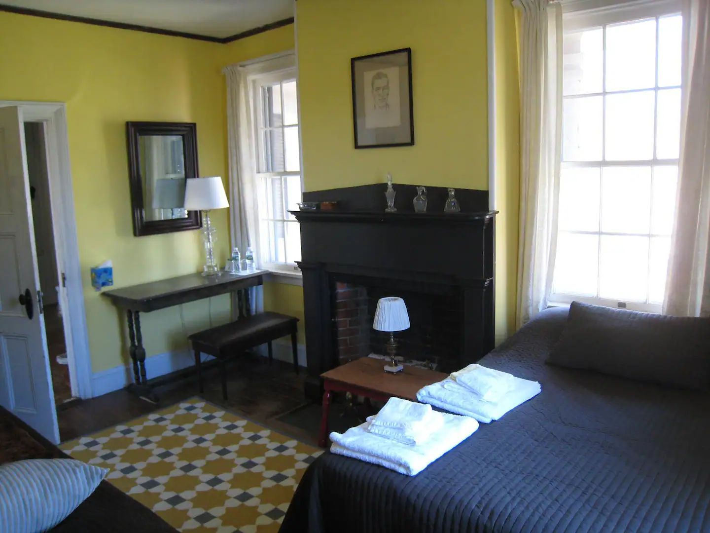 A bedroom with yellow walls and a fireplace