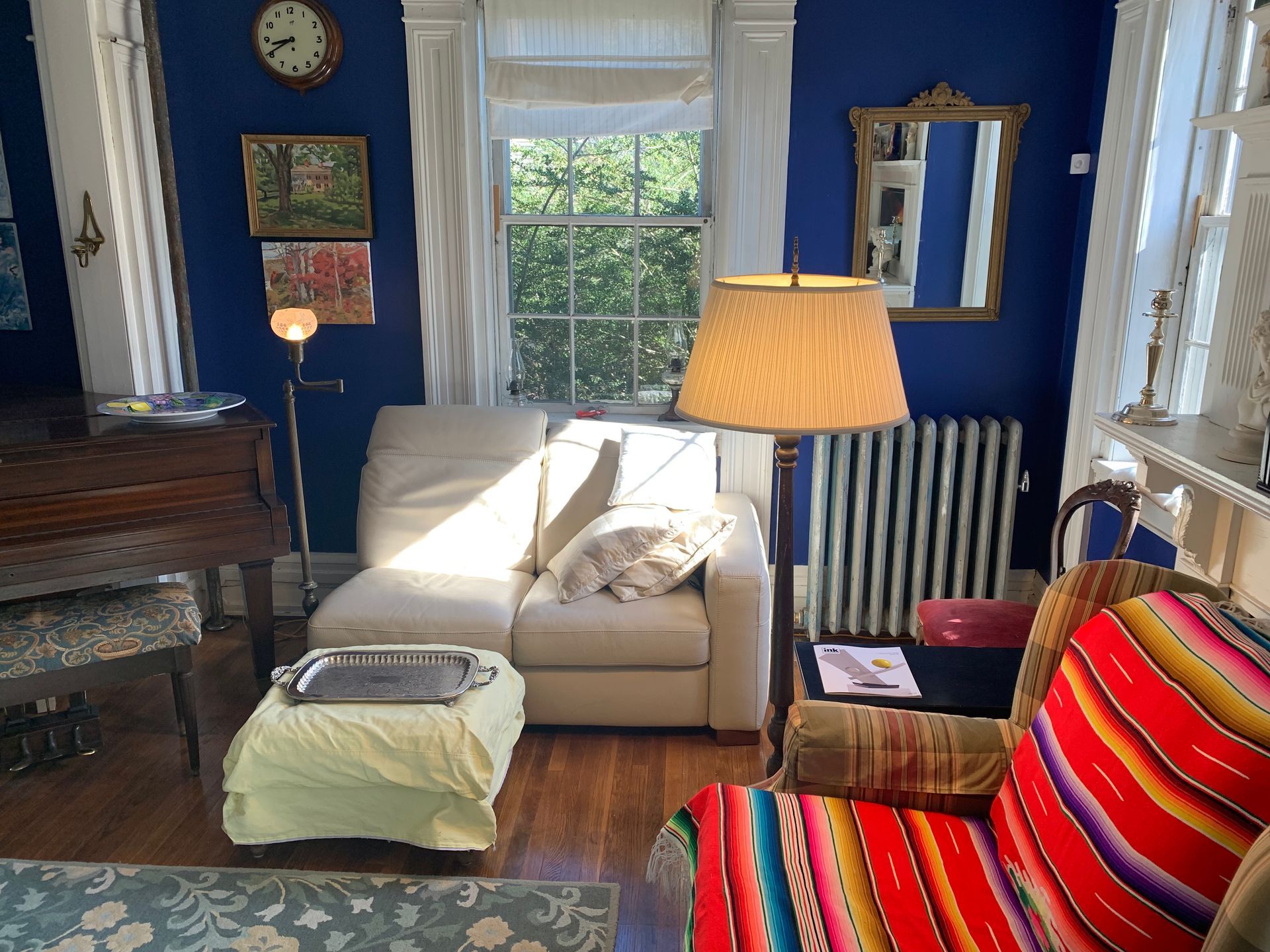 A living room with a couch , chair , lamp and ottoman