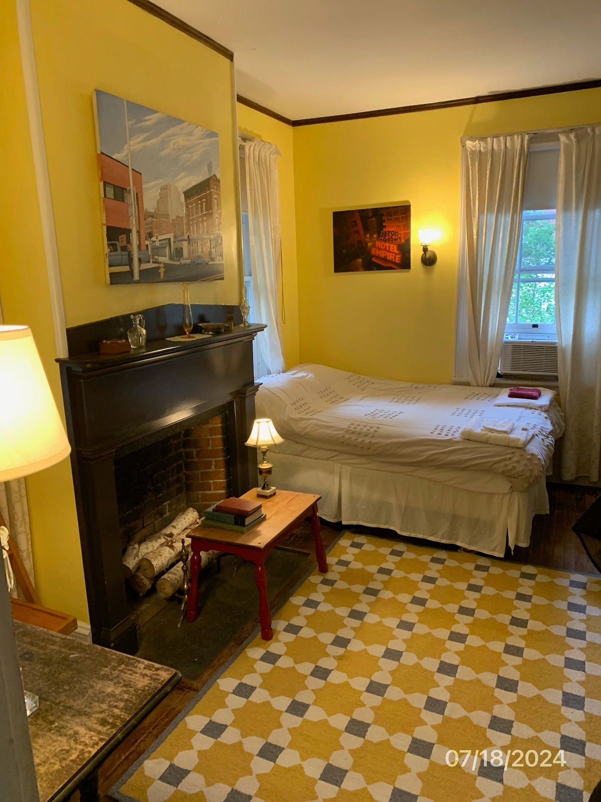 A bedroom with a bed and a fireplace with a picture on the wall