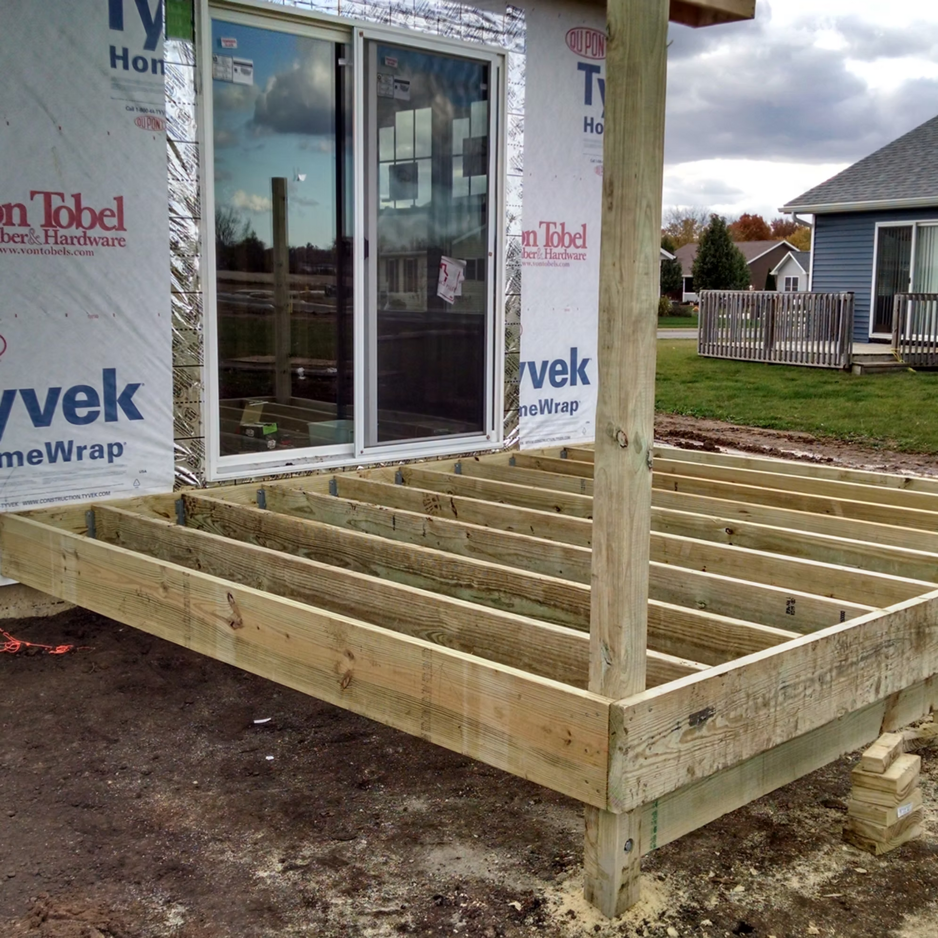 Partially built wooden deck frame attached to a house under construction