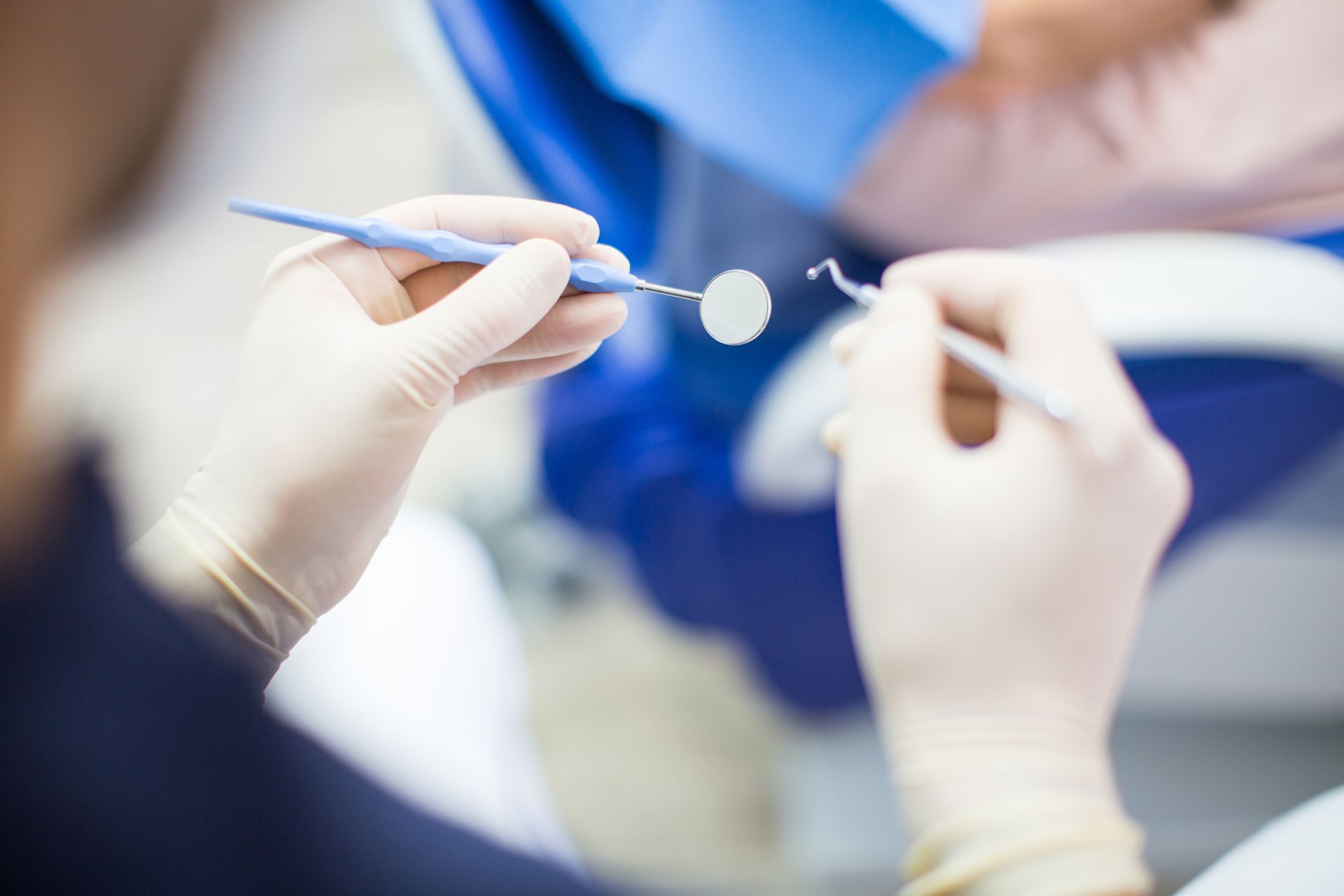 A dentist is examining a patient 's teeth in a dental chair.