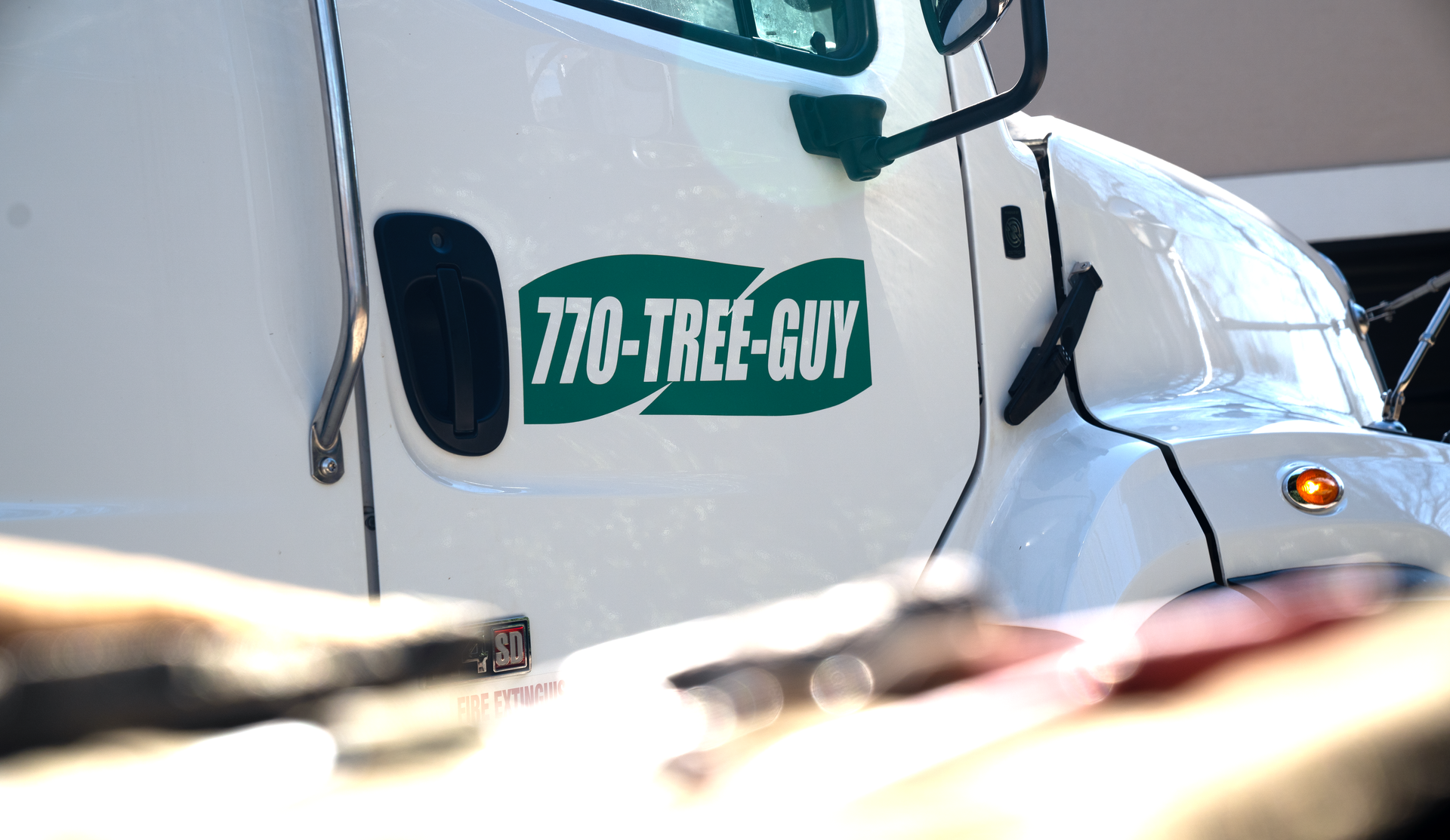 The side of a white commercial truck features a green logo with the text