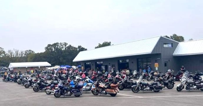 Large group of parked motorcycles outside a low building on a cloudy day