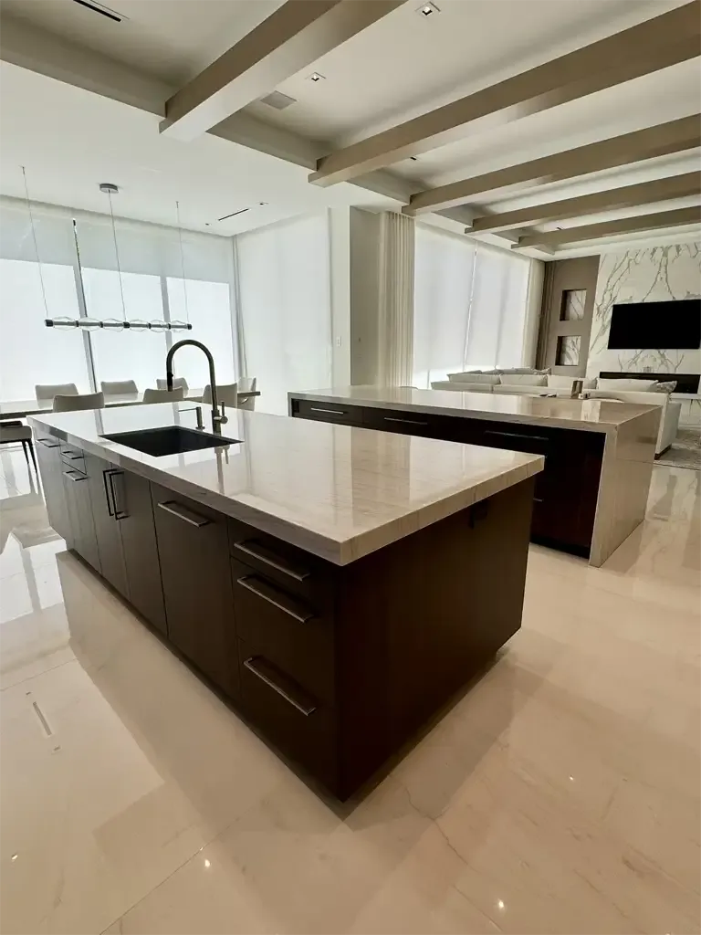Custom kitchen island with dark wood cabinetry and quartzite waterfall countertop by Kitchen & Bath Studios in Coconut Creek FL.