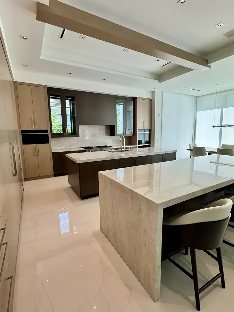 Modern two-tone kitchen with double islands, waterfall quartzite counters, and custom cabinetry in Coconut Creek Florida.