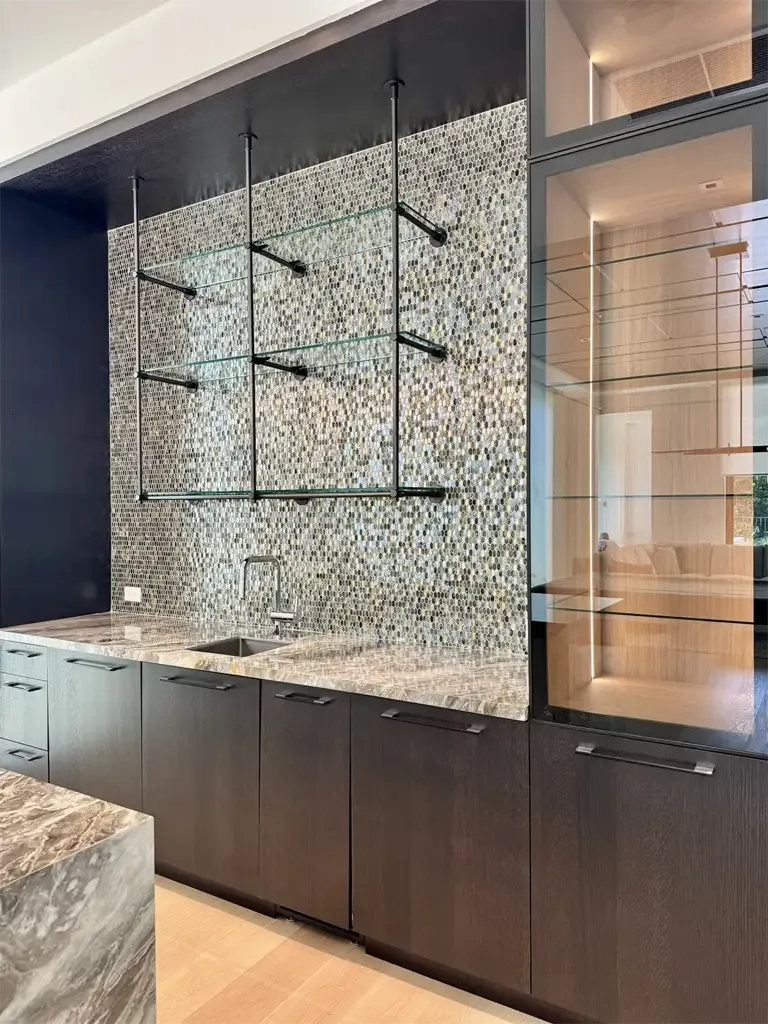 Custom wet bar cabinetry with penny tile backsplash, suspended glass shelving, and lighted display cabinets in Coconut Creek Florida.