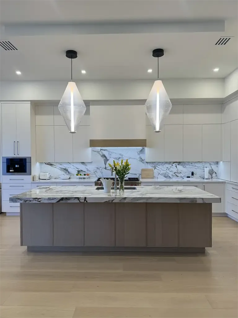 Luxury white modern kitchen with marble island by Kitchen & Bath Studios Inc