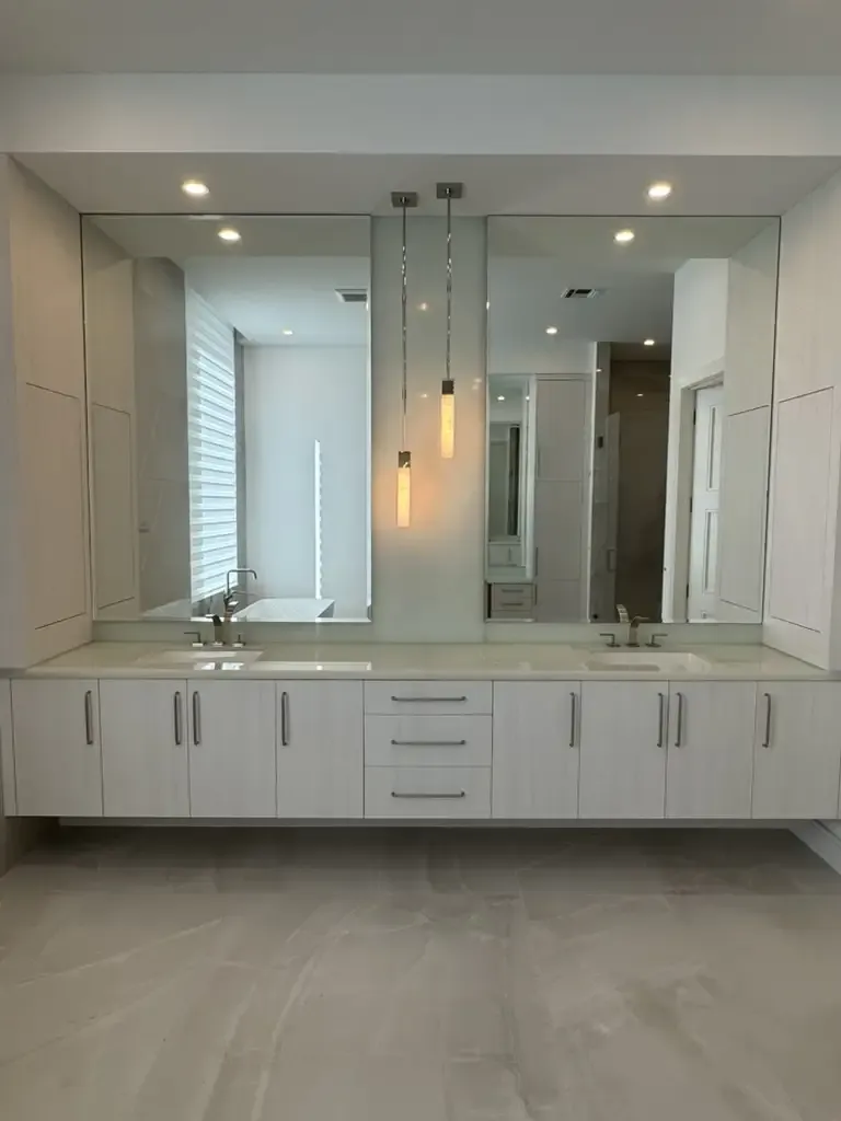 Contemporary white double vanity with floor-to-ceiling mirrors by Kitchen & Bath Studios Inc.