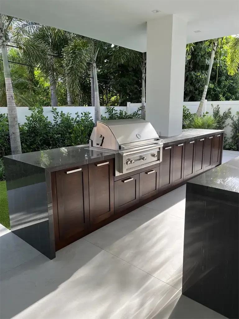 Custom outdoor kitchen with built-in grill and stone counters by Kitchen & Bath Studios Inc.